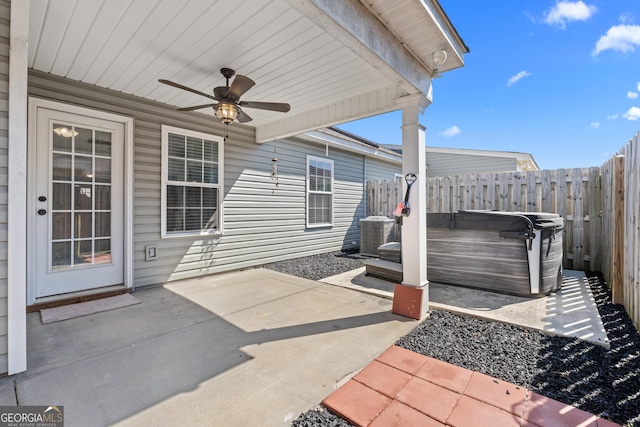 view of patio featuring cooling unit, fence, a hot tub, and ceiling fan