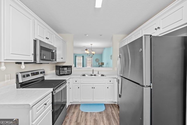 kitchen featuring a sink, light countertops, white cabinets, appliances with stainless steel finishes, and light wood-type flooring