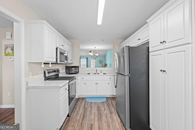 kitchen featuring stainless steel appliances, light wood-style floors, and white cabinetry