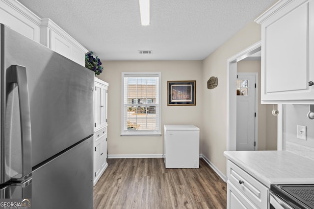 kitchen featuring visible vents, light countertops, stainless steel appliances, dark wood-style floors, and white cabinetry