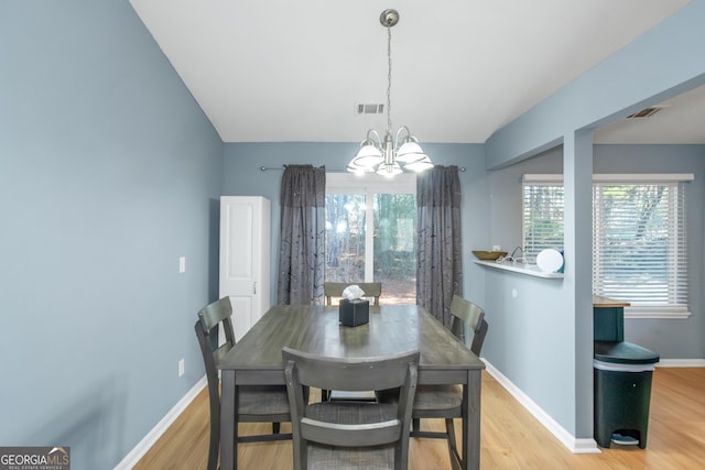 dining area with light wood-type flooring, baseboards, visible vents, and a chandelier