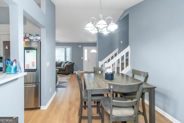 dining area with a chandelier, stairway, light wood-type flooring, and baseboards