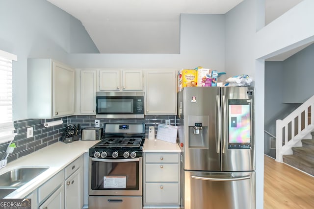 kitchen with a sink, tasteful backsplash, appliances with stainless steel finishes, and light countertops