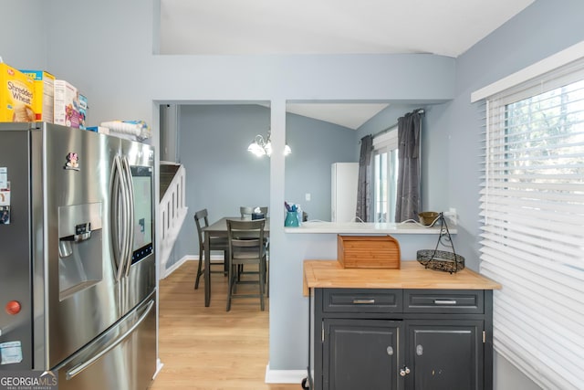 kitchen with light wood finished floors, butcher block counters, baseboards, and stainless steel fridge with ice dispenser