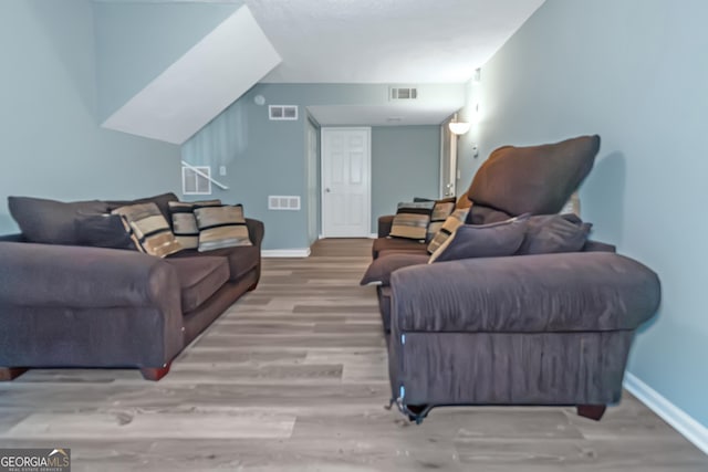 living room with visible vents, baseboards, and wood finished floors