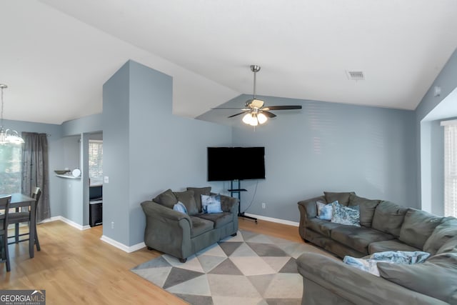 living room featuring visible vents, light wood-style flooring, baseboards, and lofted ceiling