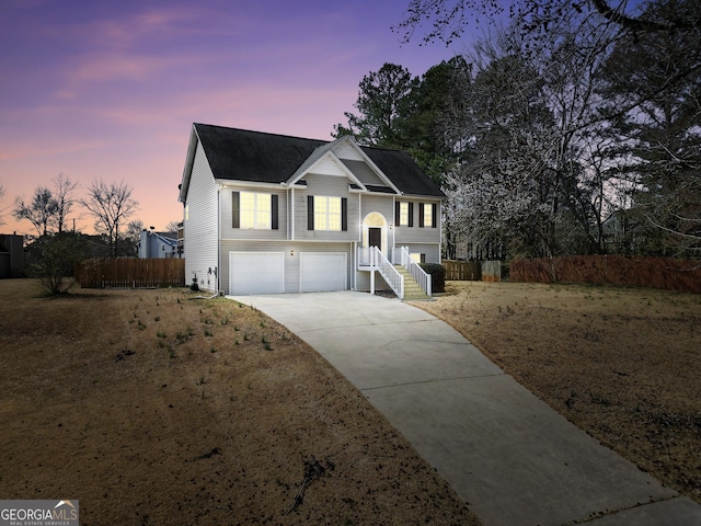 raised ranch featuring concrete driveway, fence, and a garage