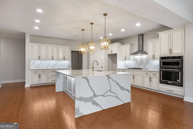 kitchen featuring a sink, dobule oven black, white cabinetry, wall chimney exhaust hood, and backsplash