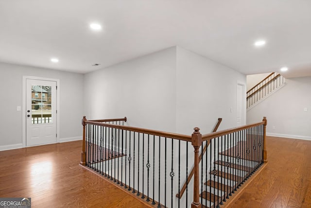 corridor with an upstairs landing, recessed lighting, baseboards, and wood finished floors