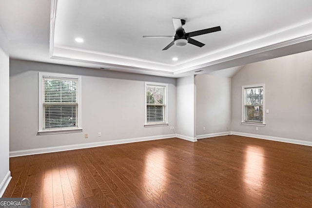 unfurnished room with a tray ceiling, baseboards, a healthy amount of sunlight, and hardwood / wood-style floors