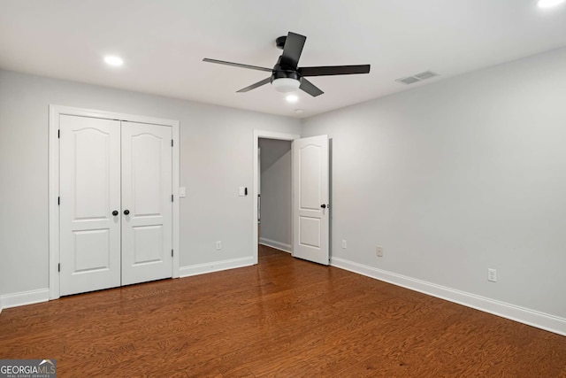 unfurnished bedroom featuring visible vents, baseboards, a closet, and wood finished floors