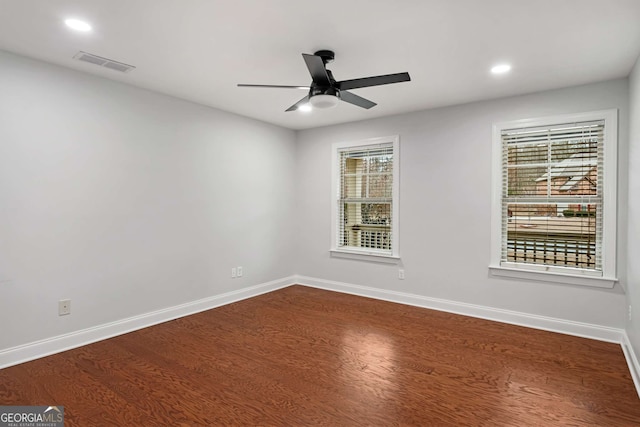 unfurnished room with visible vents, a ceiling fan, baseboards, and dark wood-style flooring