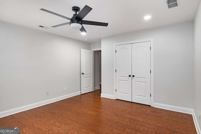 unfurnished bedroom featuring visible vents, a ceiling fan, baseboards, and dark wood-style flooring