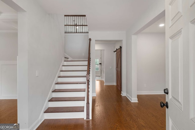 stairway featuring a barn door, baseboards, and wood finished floors