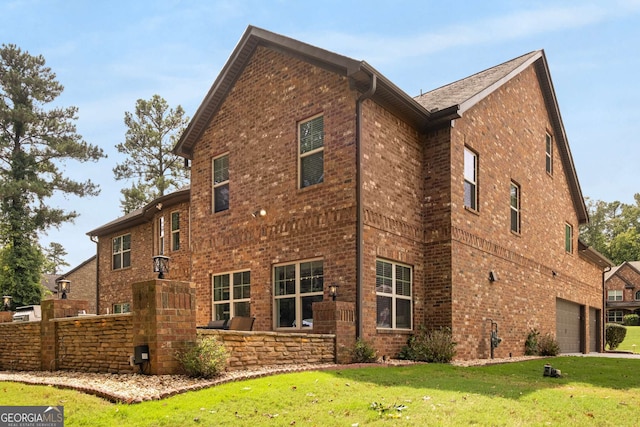 view of side of property with a garage, brick siding, and a lawn