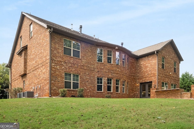 rear view of house featuring central air condition unit, a yard, french doors, and brick siding