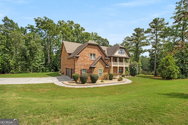 view of front of house with a front yard, a balcony, driveway, a garage, and brick siding