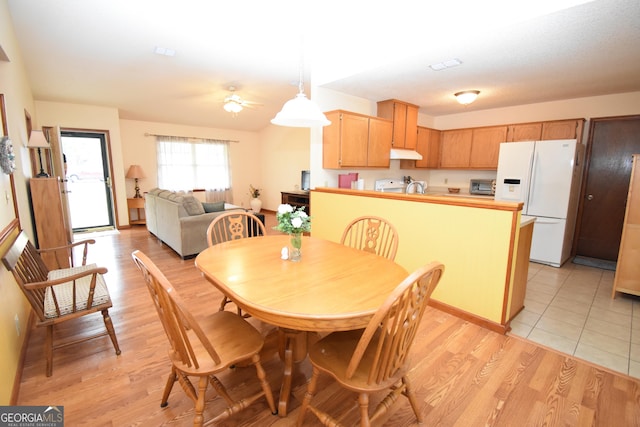 dining area featuring light wood-style floors, ceiling fan, and a toaster