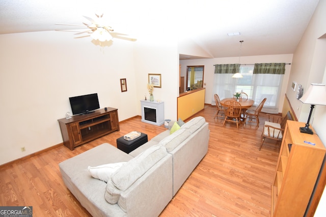 living room featuring a fireplace, baseboards, light wood finished floors, and ceiling fan