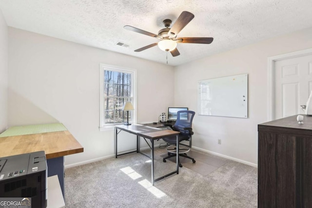 carpeted office featuring visible vents, baseboards, a textured ceiling, and ceiling fan