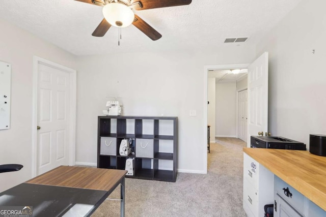 office space with visible vents, light carpet, a textured ceiling, and baseboards