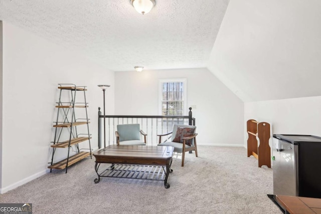 sitting room with baseboards, a textured ceiling, carpet, and vaulted ceiling