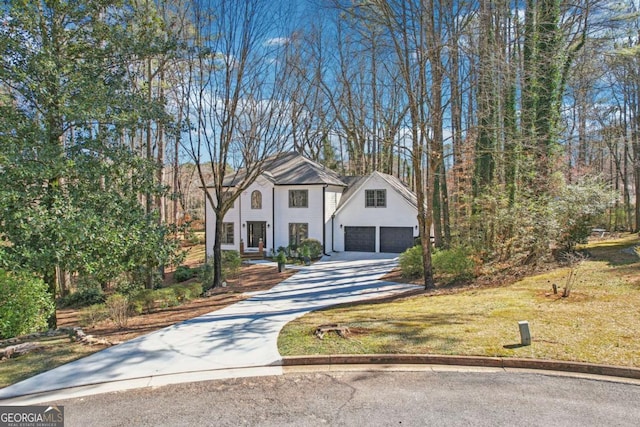 view of front of home featuring an attached garage, concrete driveway, and a front lawn