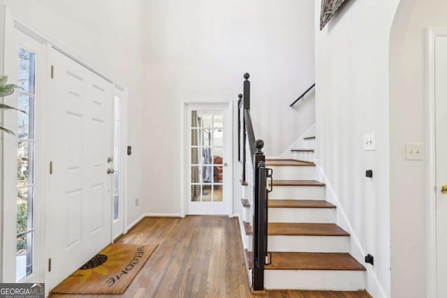 entrance foyer featuring baseboards, wood finished floors, and stairs