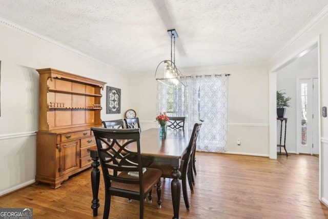 dining room with baseboards, a textured ceiling, wood finished floors, and crown molding