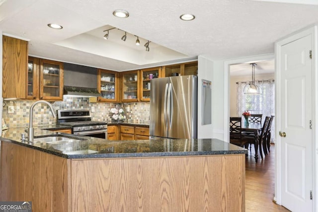 kitchen with brown cabinetry, dark stone countertops, and appliances with stainless steel finishes