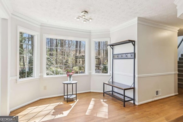 unfurnished room featuring wood finished floors, visible vents, ornamental molding, stairs, and a textured ceiling