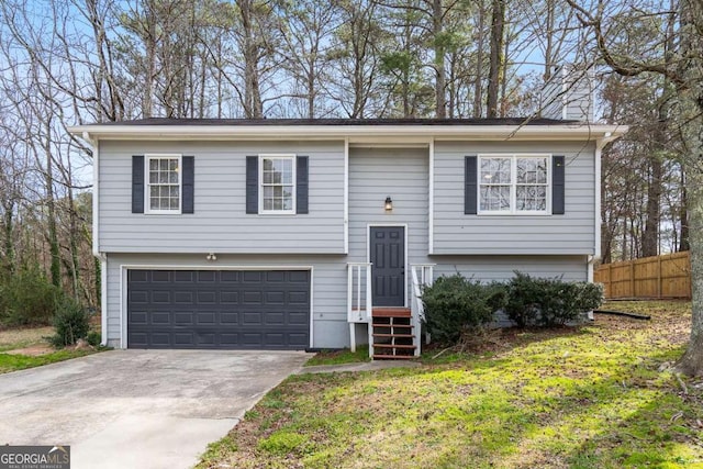 bi-level home featuring concrete driveway, a chimney, an attached garage, and fence