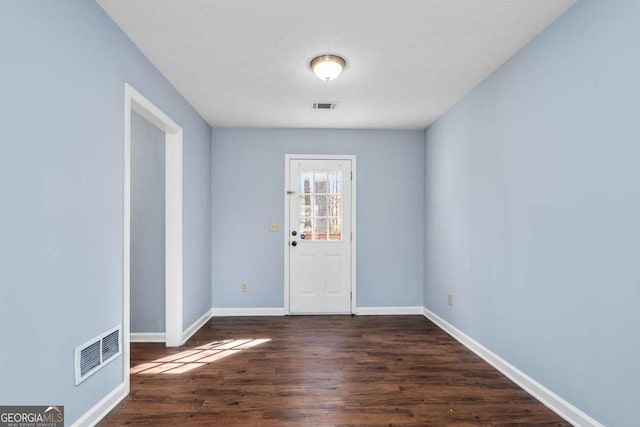 interior space with visible vents, baseboards, and dark wood finished floors