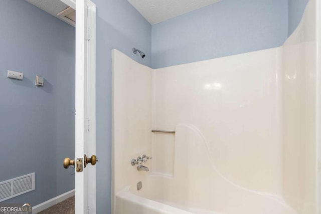 bathroom featuring tub / shower combination, visible vents, baseboards, and a textured ceiling