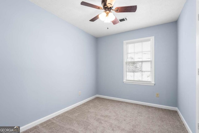 carpeted spare room with visible vents, a ceiling fan, and baseboards