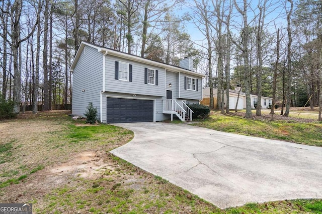 split foyer home with concrete driveway, an attached garage, and a chimney