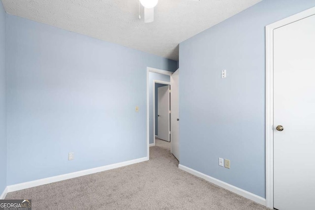 unfurnished bedroom with carpet flooring, ceiling fan, a textured ceiling, and baseboards