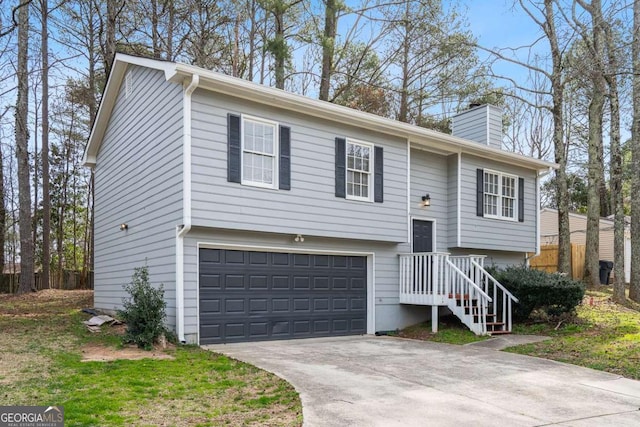 split foyer home featuring driveway, a chimney, and a garage