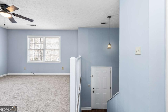 stairway with visible vents, carpet floors, a textured ceiling, and baseboards