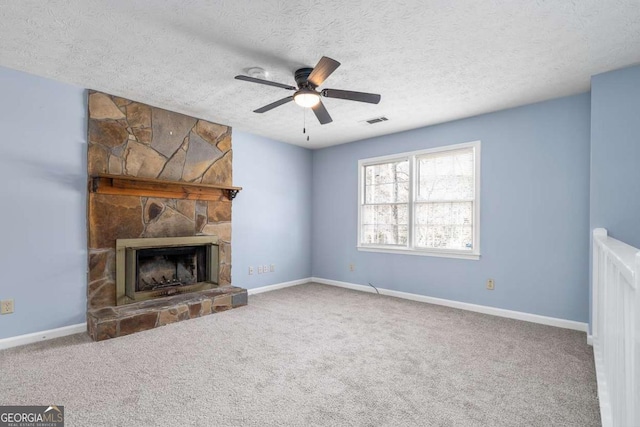 unfurnished living room with baseboards, visible vents, a stone fireplace, and carpet