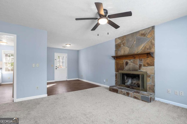 unfurnished living room featuring a fireplace, baseboards, carpet floors, and a textured ceiling