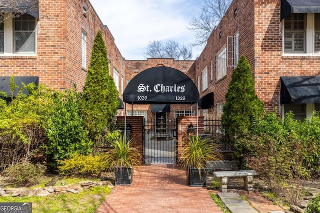 exterior space featuring brick siding, fence, and a gate