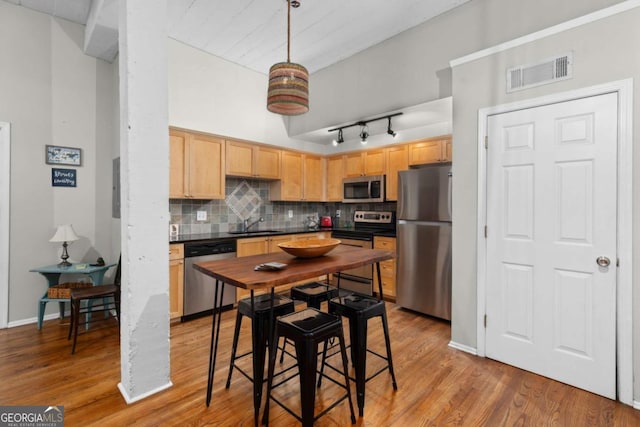 kitchen featuring visible vents, light brown cabinetry, decorative backsplash, stainless steel appliances, and dark countertops