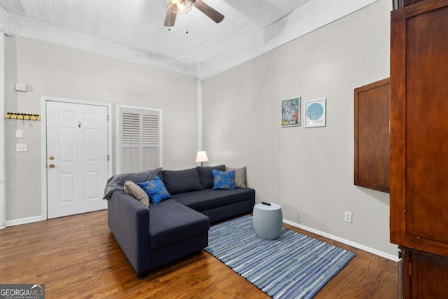 living room with ceiling fan, baseboards, and wood finished floors