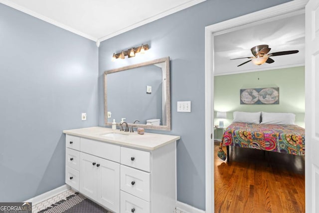 bathroom featuring crown molding, baseboards, ceiling fan, wood finished floors, and vanity