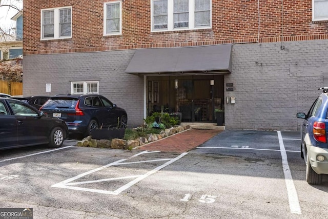 view of exterior entry featuring uncovered parking and brick siding