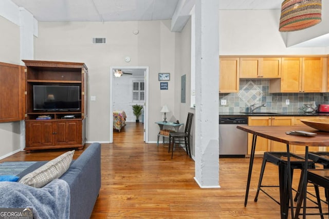 interior space featuring dark countertops, backsplash, dishwasher, light wood-style flooring, and a sink