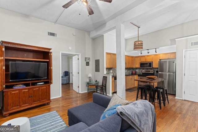 living area featuring visible vents, baseboards, ceiling fan, light wood-type flooring, and electric panel