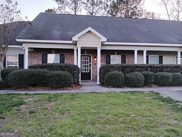 view of front of property with brick siding, a front lawn, and roof with shingles