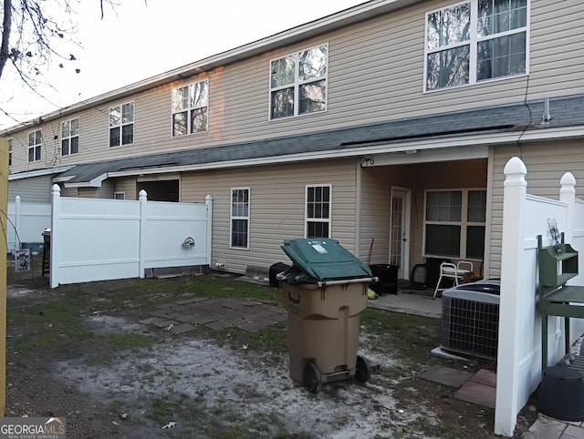 back of house featuring fence, central AC, and a shingled roof